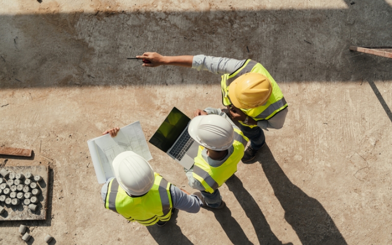 Top view, Team engineer building inspection use tablet computer and blueprint working at construction site.