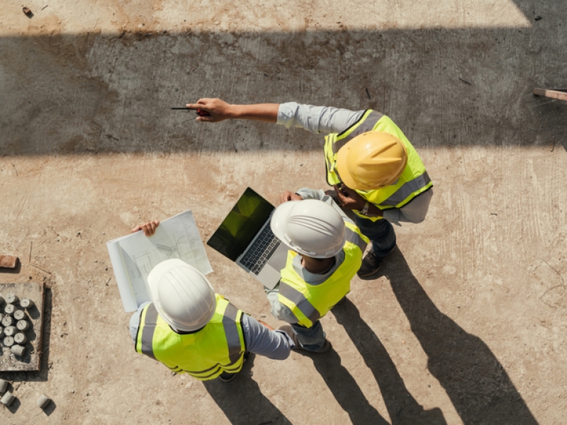 Top view, Team engineer building inspection use tablet computer and blueprint working at construction site.